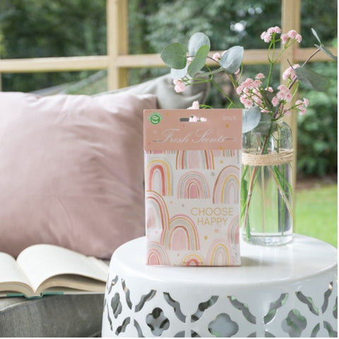 Choose Happy pink sachet sitting on white side table.