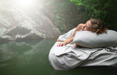 Woman laying in a serene forest on a mattress