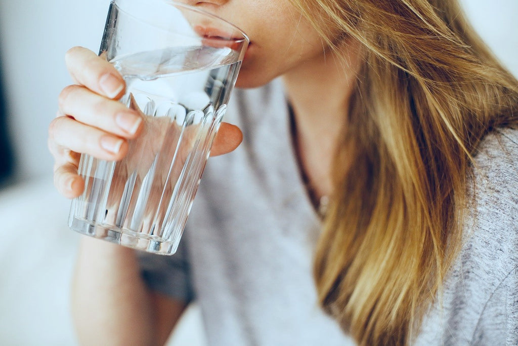 Woman drinking from a glass of water after taking probiotics