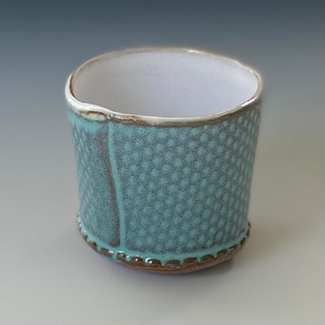Slab built cup with dotted texture and with glossy glazes of turquoise for the exterior and white for the interior
