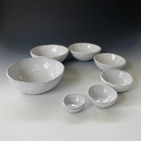 Seven nesting pinch pots in white glaze set in a spiral of increasing size