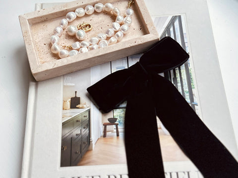 Image of big velvet hair bow and pearl jewellery resting on Athena Calderones book life is beautiful