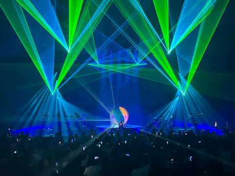 Janet Jackson performs on stage with lasers shining blue and green beams