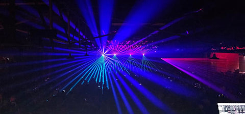 Colorful laser beams project over the crowd.