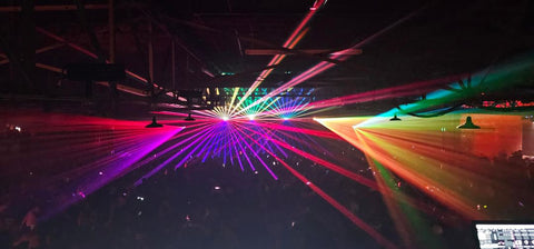 Colorful laser beams project over the crowd.