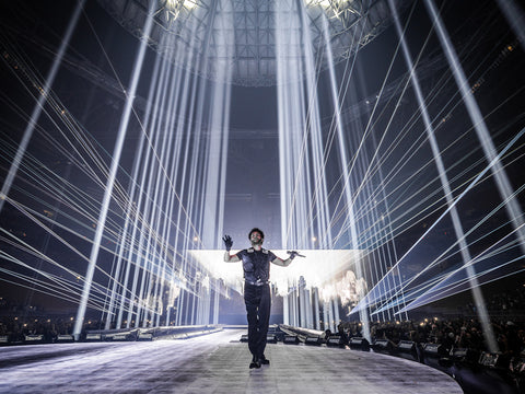 The Weeknd performs with white laser beams shining in the background