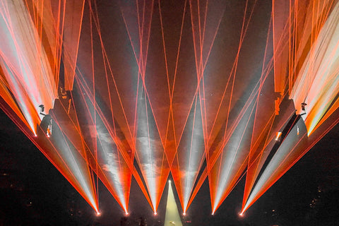 Orange and white laser beams shine over the crowd.