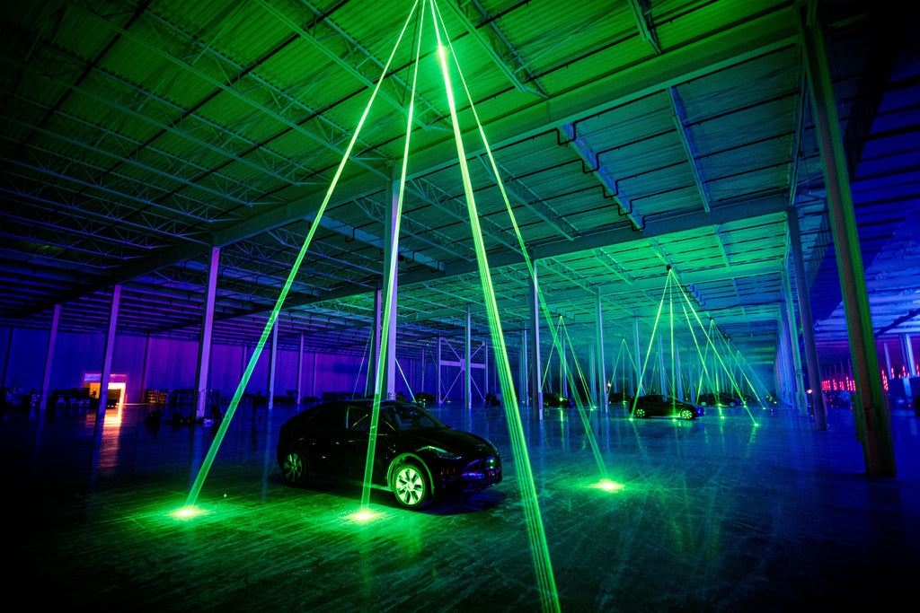Green lasers beam project down on to Tesla vehicles