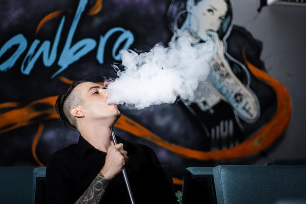 homme utilisant un vaporisateur et expirant un grand nuage de vapeur