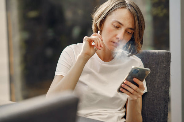 person vaping while looking at cell phone