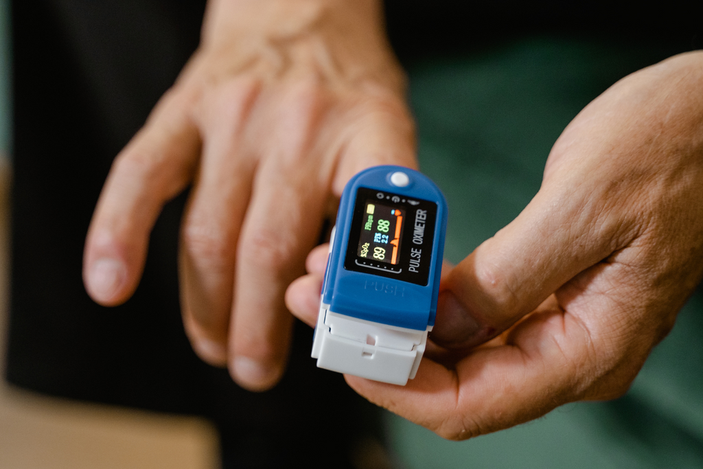 A person easily uses a pulse oximeter to test for covid-19 by placing it on their finger and pressing the start button