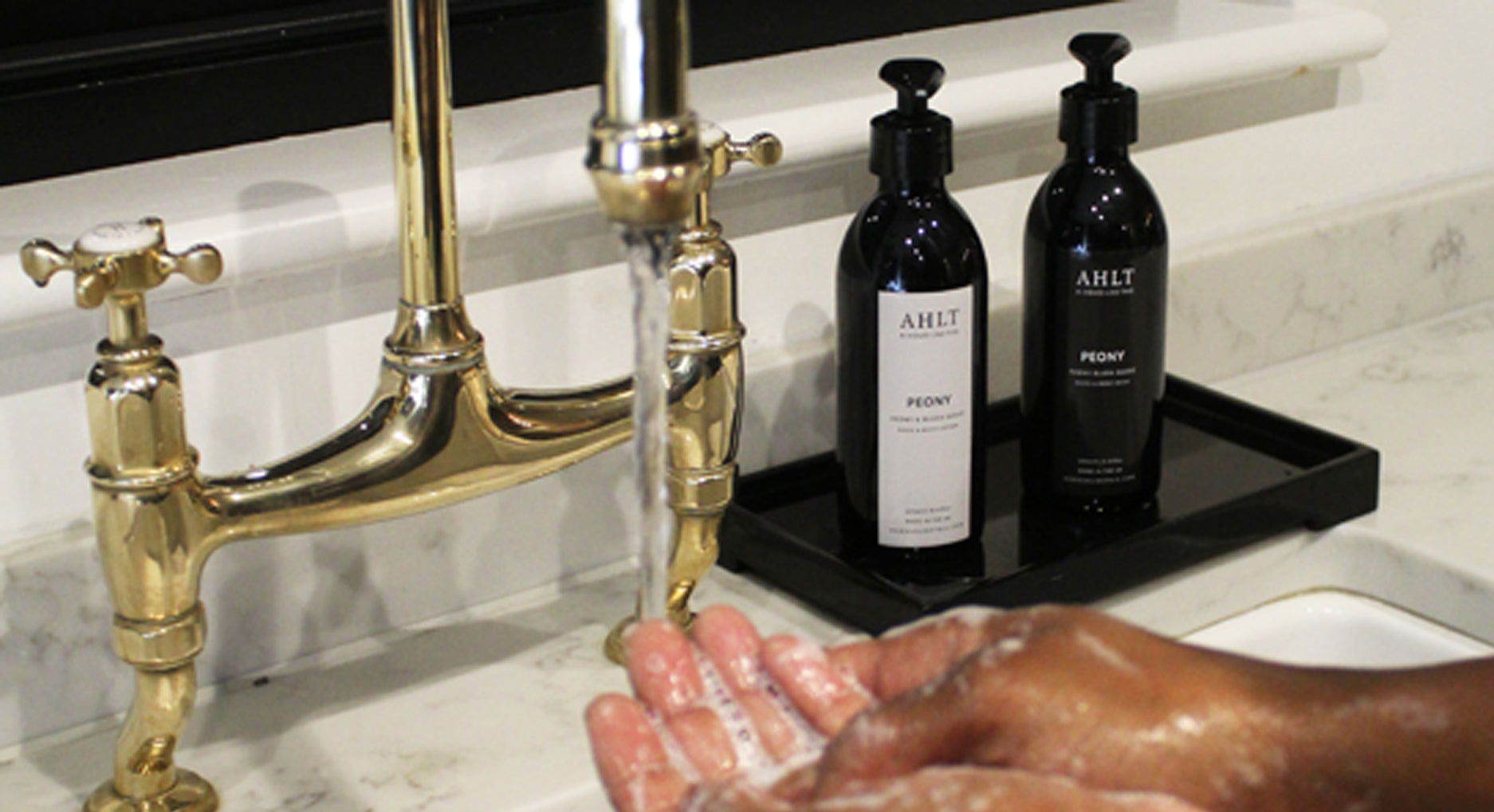 HANDWASH AND LOTION NEXT TO MARBLE SINK IN KITCHEN WITH COPPER TAPS