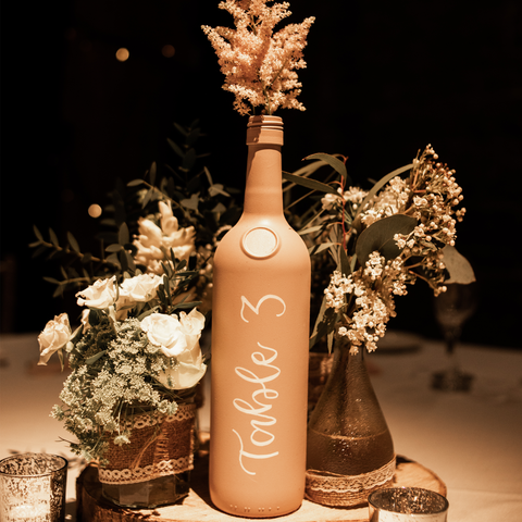 wedding table number hand lettered on pastel bottle in calligraphy