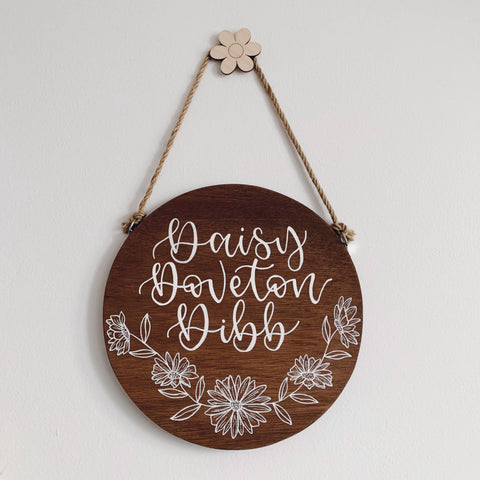 Brown wooden sign made for home decoration, with white calligraphy lettering saying there’s no place like home