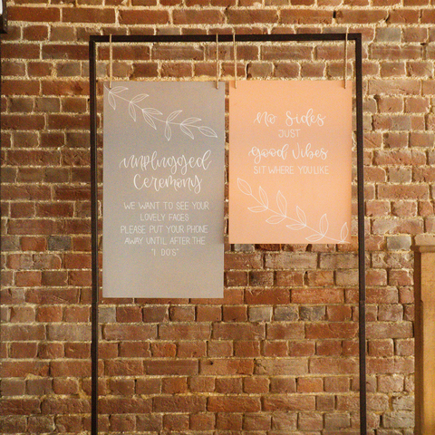 Hanging wedding signage, with unplugged ceremony sign in grey and seating plan in pastel pink. Spring theme