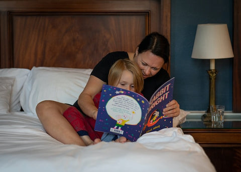 Mum reading bedtime story to toddler in bed