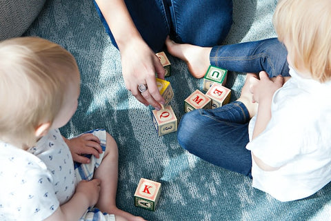 Two toddlers playing with wooden alphabet blocks