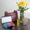 A pill wallet and daily pill organiser next to a handbag and vase full of beautiful yellow flowers 