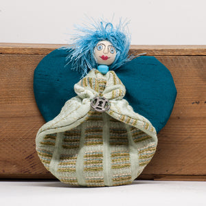 14cm high hanging lavender filled angel with deep teal coloured wings, light blue shiny hair and a pale mint green, gold, beige and blue embossed pattern on the body. She holds a little circular trinket with a key hole shape in the middle. 