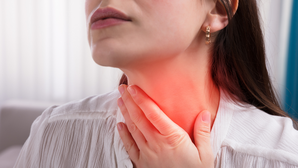 Woman touching neck where throat is sore 