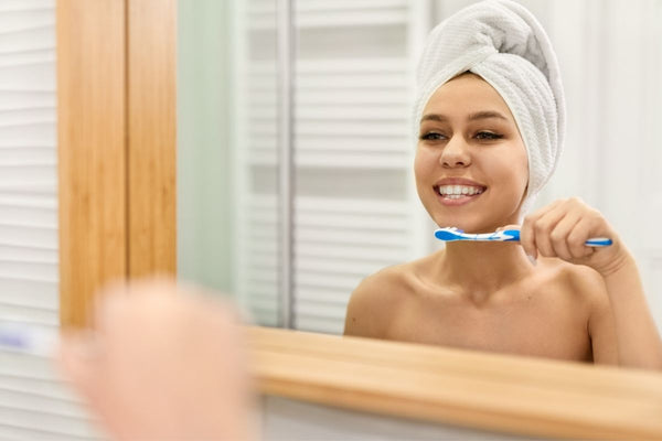 Girl brushing teeth while looking at bathroom mirror