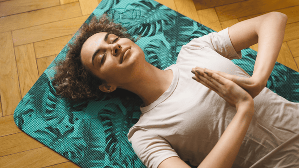 Woman laying on yoga mat practicing meditation 