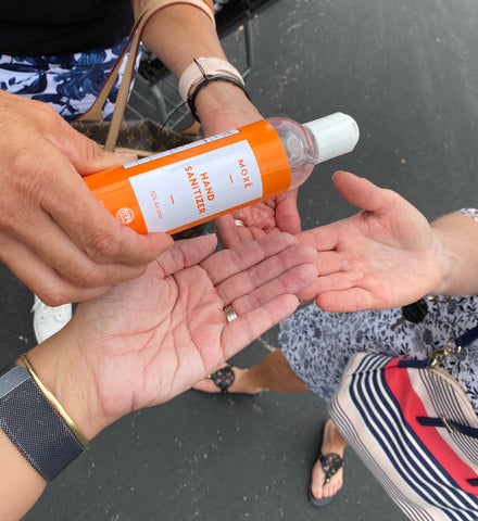 Group of people reaching out to use Moxe hand sanitizer 