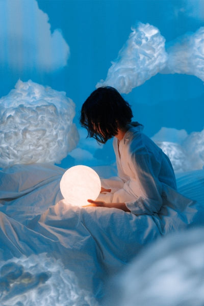 Girl holding globe in abstract dream world with clouds 