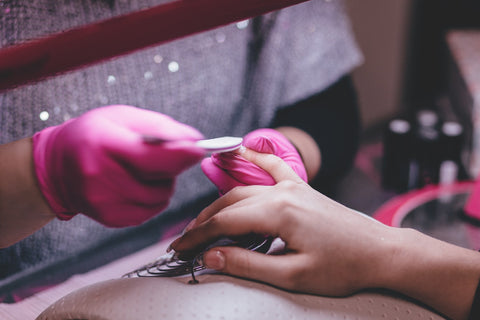 woman damaging her nails and cuticles with acrylic application during a manicure which can be resolved by using essential oils for nails and dry cuticles