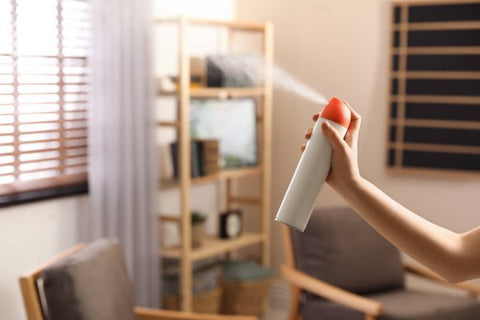 woman spraying air freshener in her home