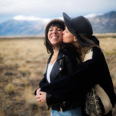 two women kissing with mountains in the background