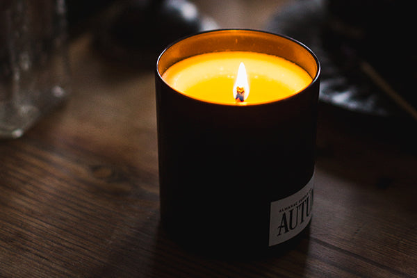 Lit Autumn Candle on a wooden surface in a moody room