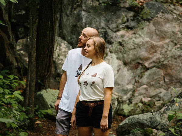 Lush woods surround 2 people hiking