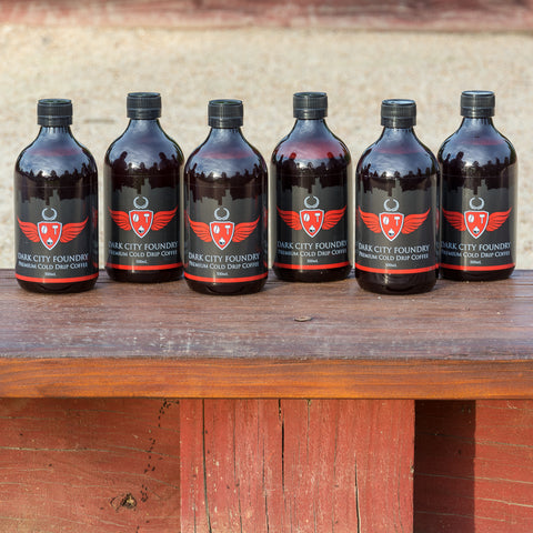 6 pack of 500ml bottles of cold brew coffee lined up in a row at the park.