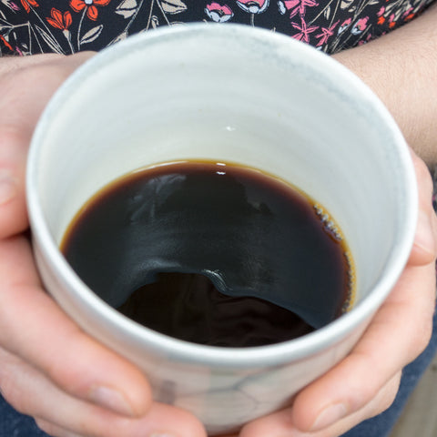 cold brew coffee in a mug being held between two hands