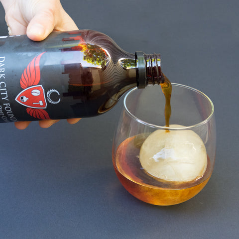 pouring cold brew coffee into a glass over ice.