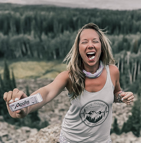 woman on mountain holding a pack of Apollo Energy Gum with piece in mouth