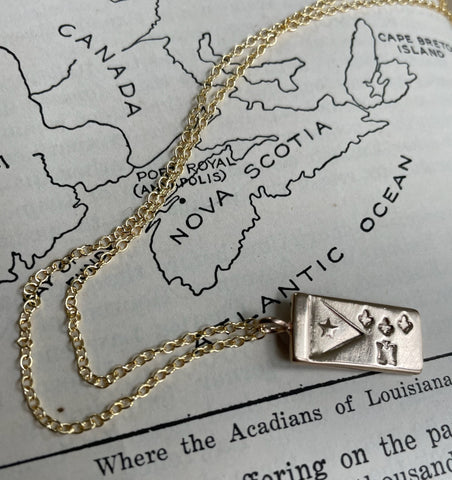 MIMOSA Handcrafted's Bronze Acadian Flag Necklace Is Displayed On A Map of Canada