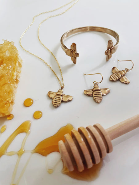 MIMOSA Handcrafted's Bee Jewelry Collection is Displayed Next to a Honeycomb