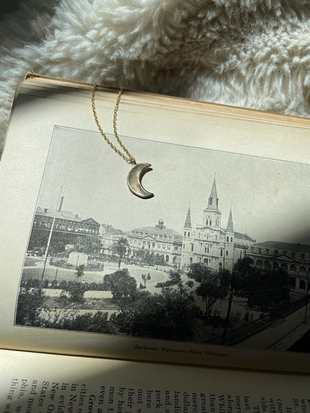 MIMOSA Handcrafted's Crescent Moon Necklace Rests on a Photo of New Orleans, Nicknamed the Crescent City