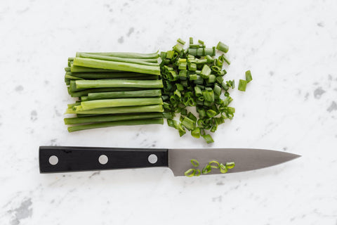 green onion and knife on top of marble counter