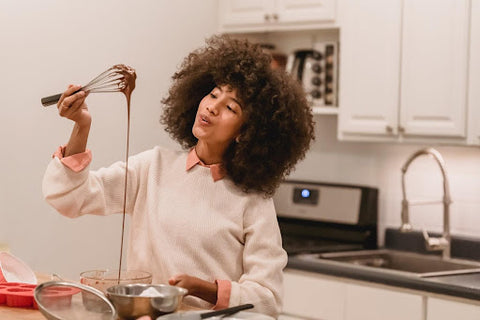 Woman holding whisk with chocolate sauce