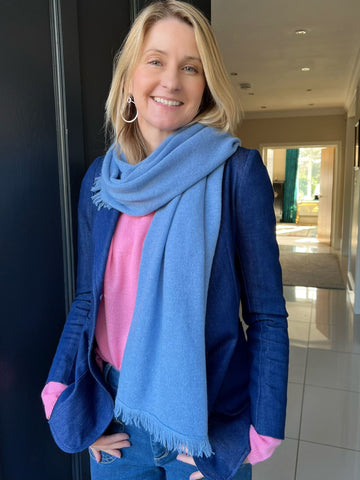 Women wearing a blue cashmere scarf over her shoulder, a pink cashmere jumper and a navy blazer.