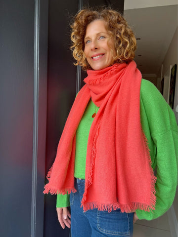 Women wearing a green cashmere jumper and a coral scarf wrapped around her neck.