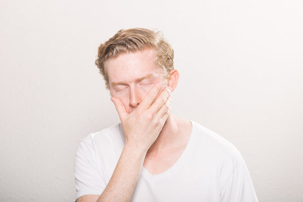 man yawning into his hand with closed eyes