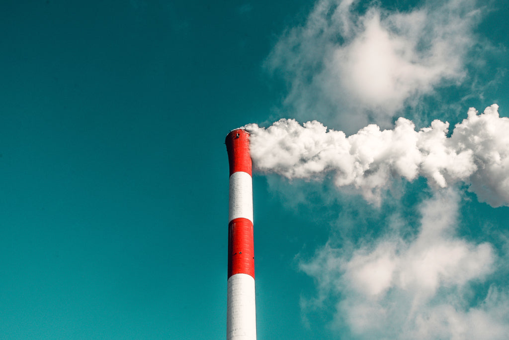 red and white smoke stack emitting steam under a blue sky