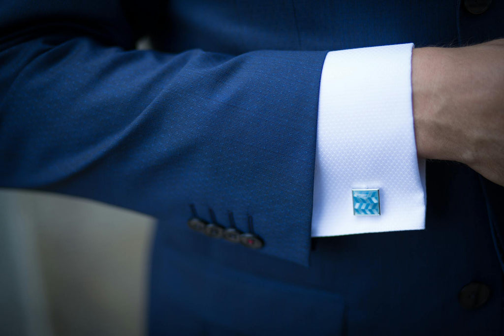 man wearing blue cufflinks with a blue suit
