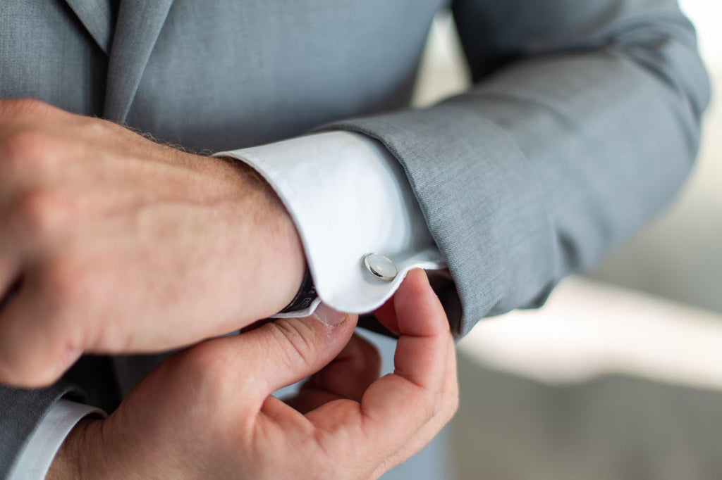 man using cufflinks with a white dress shirt and grey suit
