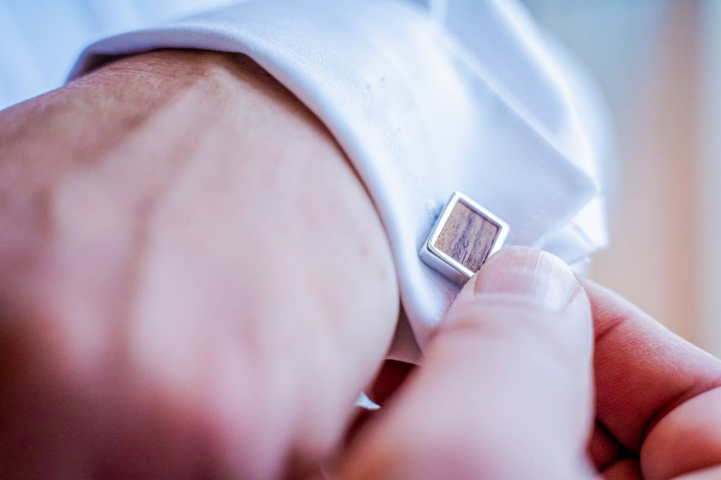 man wearing white shirt while using wooden and silver cufflinks