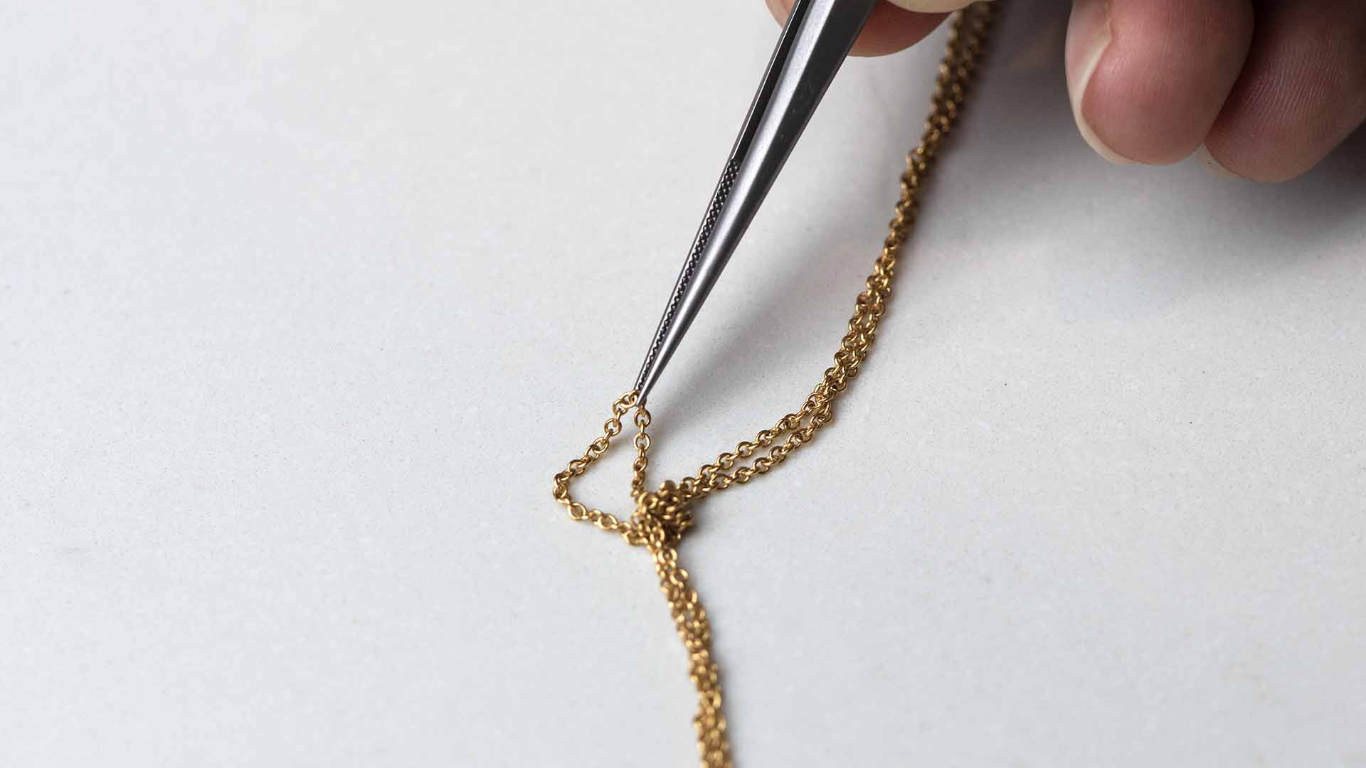 tweezers untangling gold necklace